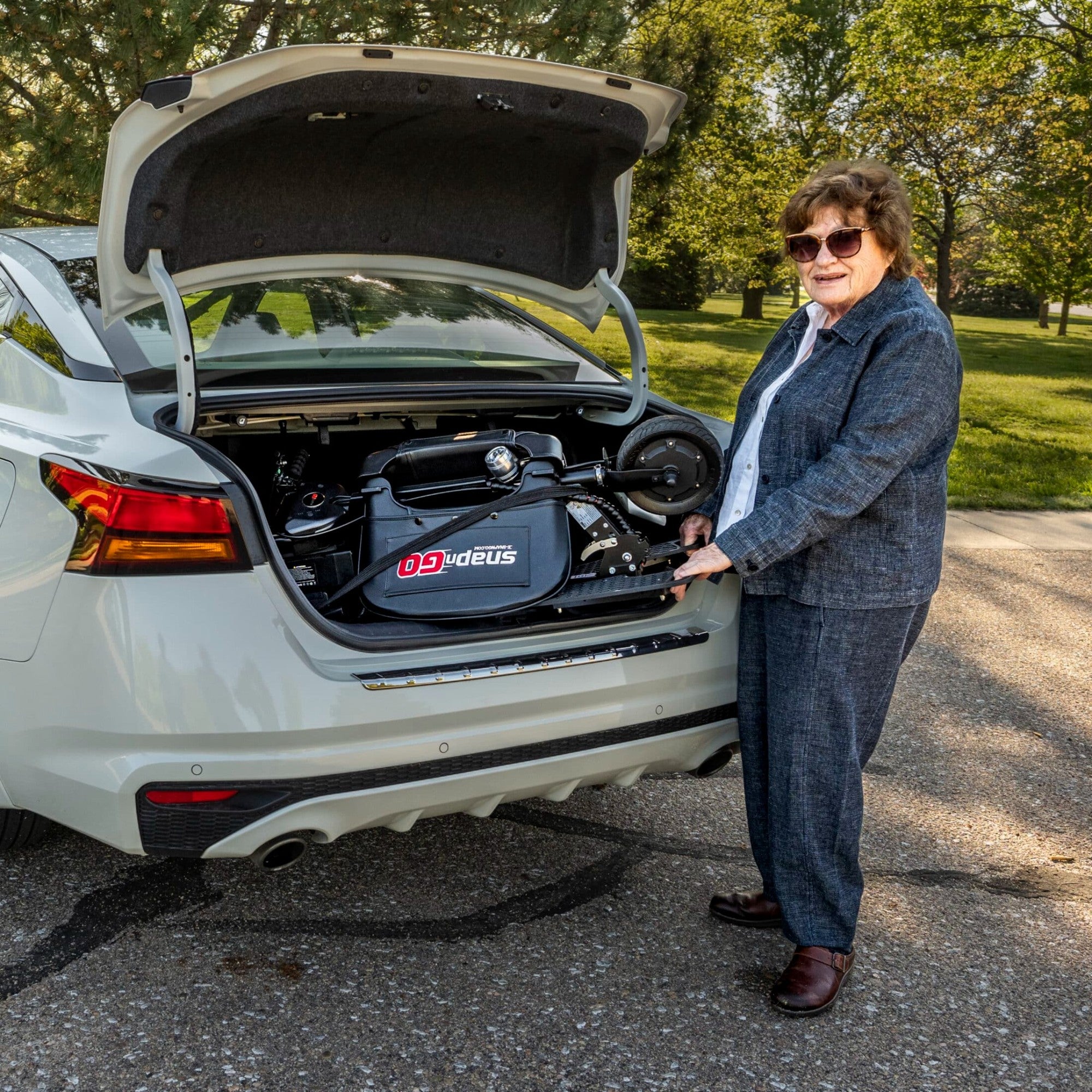 Senior loading SnapnGO Sport Mobility Scooter into a car trunk for travel